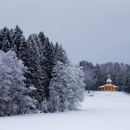 Snow covered chapel and trees in the winter forestの写真素材