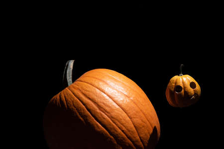 Small Halloween pumpkin orbits in space like a moon around large planet one.の写真素材