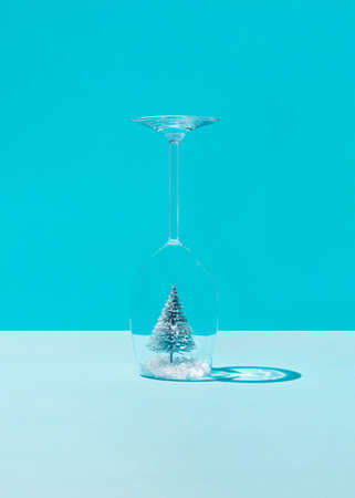 Christmas tree in the snow inside a wine glass against blue background.の写真素材