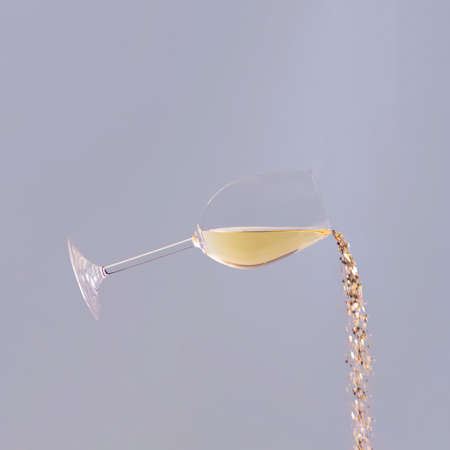 Confetti comes out of a glass of wine against blue background.の写真素材
