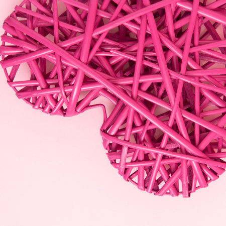 Piece of red wicker heart on a pink background.の写真素材