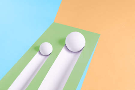 Two white balls roll downhill and leave a trail on a multicolor background. Abstract minimal...
