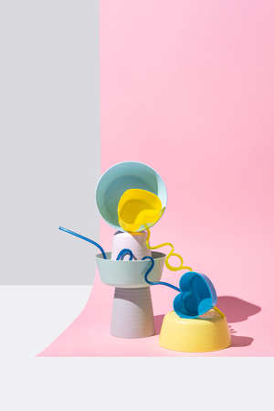 Equilibrium installation with pastel colored plastic bowls on a pink background. Abstract concept....
