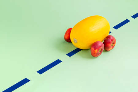 Honeydew like a car with flat peach wheels on a green background. Minimal abstract summer concept. Isometric. Rectangle layout with copy spaceの写真素材