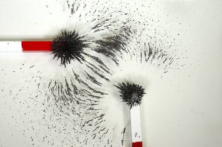 The lines of forces around two magnets with merging magnetic fields, but arranged in an angle, the...