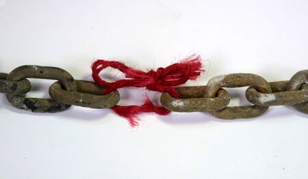 The weakest link; a massive chain where one link is replaced with a piece of red thread with frays.