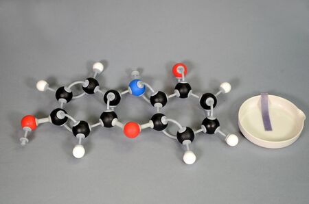 Molecule model of Litmus in blue state, with a piece of blue litmus paper on a white plate. White is...