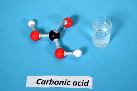 Molecule model of Carbonic Acid along with sample in a beaker. White is hydrogen, black is carbon, and red is oxygen.の写真素材