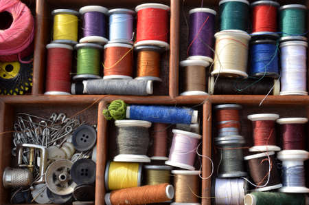 View into a workbasket with spools of sewing thread in many colours.の写真素材