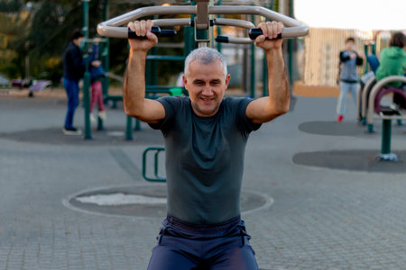 Mature man working out in the gym and leading a healthy and active lifestyle. Outdoor sports area...