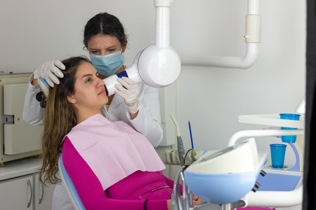 A radiologist take a picture of teen girl patient in the X-ray dental office in the hospitalの写真素材