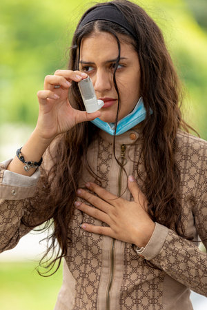 Teenager girl using asthma inhaler in parkの写真素材