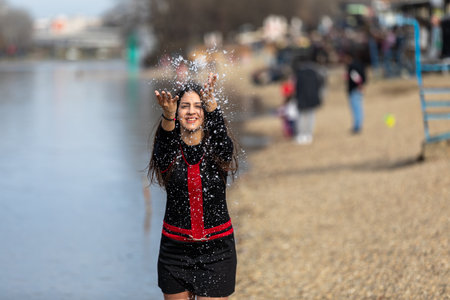Mid-Motion shot: smiling teen girl sitting on the shore of lake and throwing water in the airの写真素材