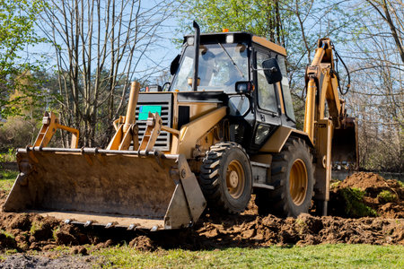 An bucket excavator in the village paves the way, digs soil and clears land.の写真素材