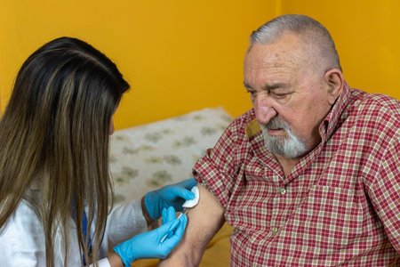 The doctor gives the vaccine to the pensioner at his homeの写真素材