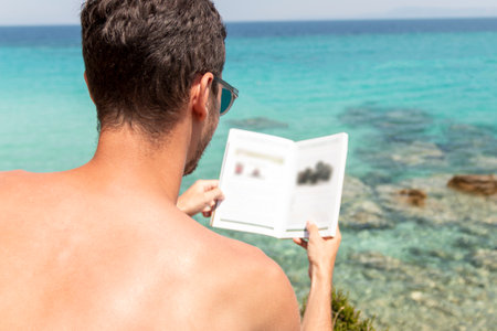 Young man is lreading a book next to the see.Summer vacation concept.の写真素材
