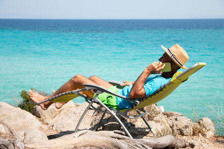 Mature man talking by mobile phone on beach. Business tripの写真素材