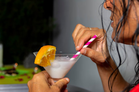 Happy romantic couple celebrating,  holding glasses of cocktails with fruits and drinking straws. Wedding anniversary, Date night, Valentines day conceptの写真素材