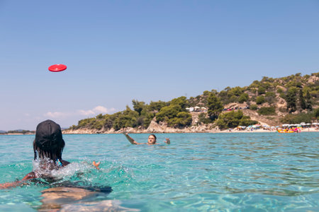 Happy young couple playing with a plastic disc in the sea. Travel, vacation and funの写真素材