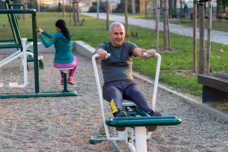 Mature man working out in the gym and leading a healthy and active lifestyle. Outdoor sports area with equipment, facilities for working out, stretching, cardio and strength physical activity.の写真素材