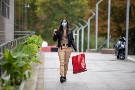 Beautiful woman enjoying in shopping.  with bags and disposable coffee cup walking on sidewalk.Portrait of smiling young student holding shopping bags.の写真素材
