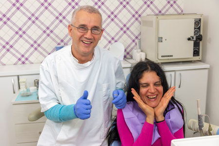 Team of patient smiling happily and dentist showing thumbs up. Concept of happy patients and dentistsの写真素材