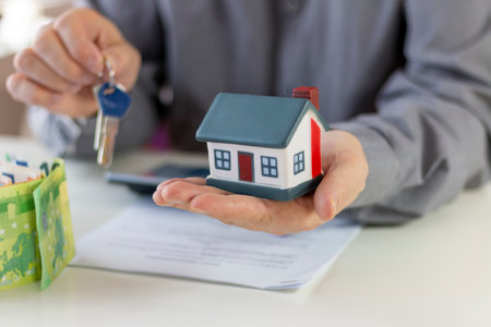 Real estate broker holding key and house model.  Offer of purchase house, rental of Real Estate. Giving, offering, demonstration, handing house keys.の写真素材