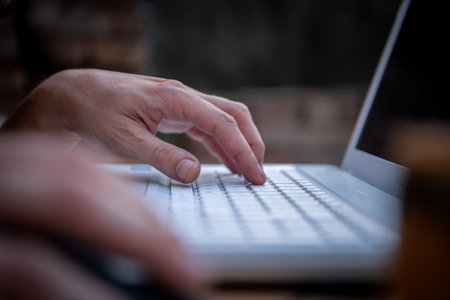Close-up View of Male Hands Working on Laptop Outside the House. A businessman is Working on his Notebook and Typing on Keyboard and Surfing the Internet.の写真素材