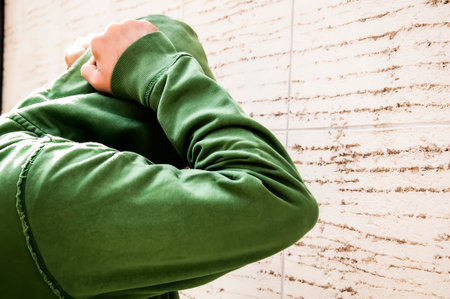 Mid Aged Man With Beard In Green Sweatshirt With Hood Is Feeling Anxious And Sad, Standing Next To The Wallの写真素材