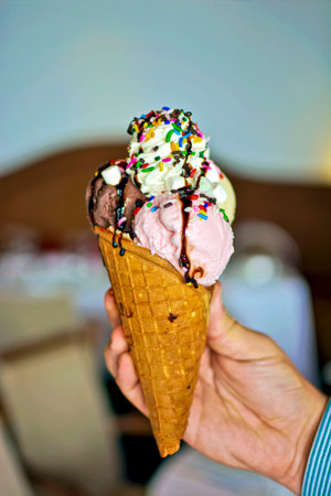 Close up View of Female Hand Holding Colored Ice Cream Coneの写真素材