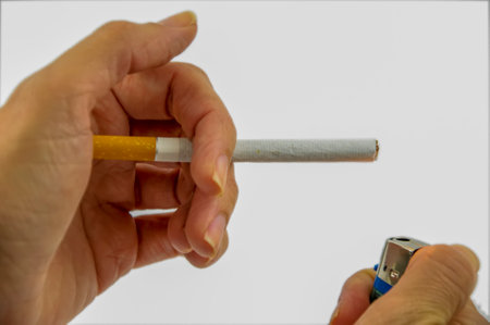 Smoking addiction concept. Woman fingers holding cigarette lighter and preparing light the cigaretteの写真素材