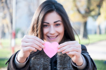 Attractive young long haired brunette with pink heartの写真素材