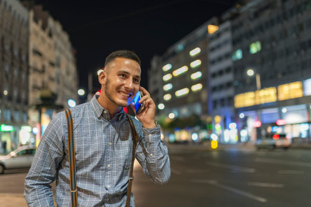Handsome Young Adult in Illuminated City Street Talking over his Smart Phoneの写真素材