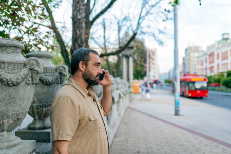 Mid Adult Bearded Man Talking in the City Streets Using his Smart Phoneの写真素材