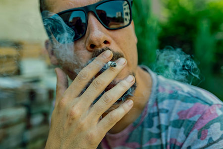 Handsome Man Smoking a Cigarette Outdoor In a Sunny Day