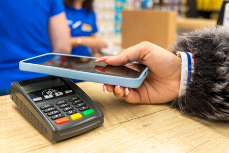 Paying with mobile phone in hand on the payment terminal