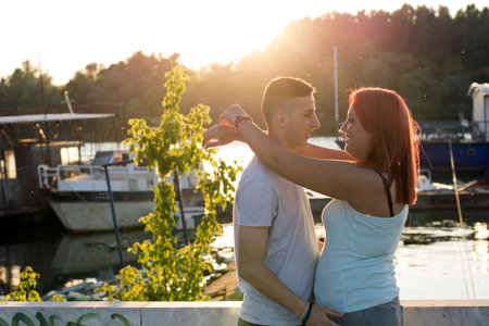 Two young and attractive lovers showing sweetest emotions near the river bank during sunsetの写真素材