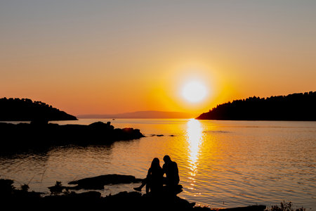 As the sun dips below the horizon, casting a warm orange glow across the sky, a striking silhouette...