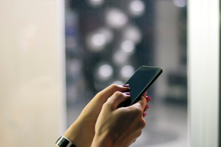Woman with Red Nails Using a Smart Phone in the Streetの写真素材
