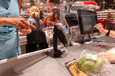 A happy woman  shopping at supermarket and standing at store checkout and pays for groceriesの写真素材