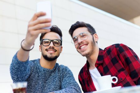 Outdoor portrait of two young entrepreneurs taking a selfie at coffee shop.の写真素材