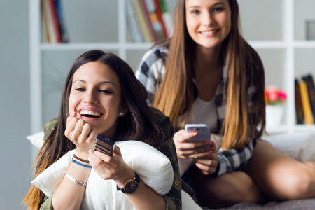 Portrait of two beautiful young woman staying on sofa at home.の写真素材