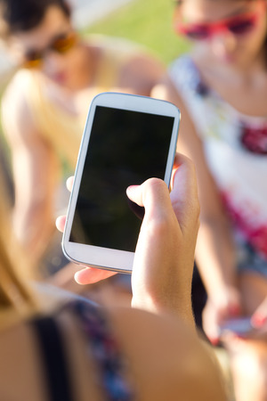 Outdoor portrait of group of friends texting with their smart phones in the park.の写真素材