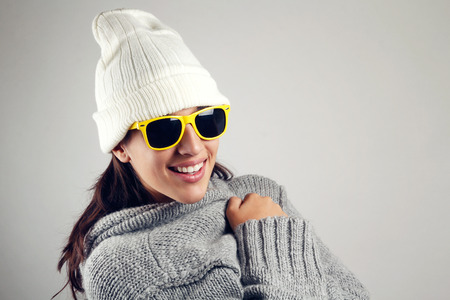Winter scene of pretty young woman with white wool cap and yellow sunglassesの写真素材