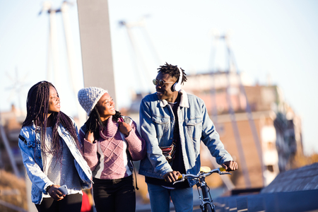 Portrait of group of three friends walking and laughing in the street.の写真素材