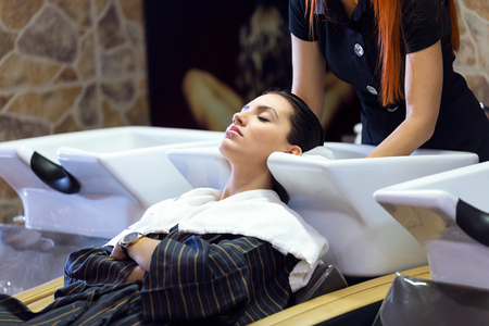 Portrait of beautiful young woman washes hair in a beauty salon.の写真素材