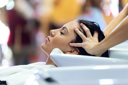 Portrait of beautiful young woman washes hair in a beauty salon.の写真素材