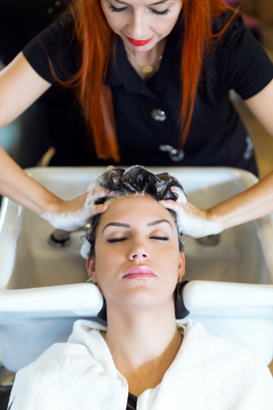 Portrait of beautiful young woman washes hair in a beauty salon.の写真素材