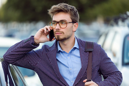 Portrait of handsome young businessman using his mobile phone in the street.