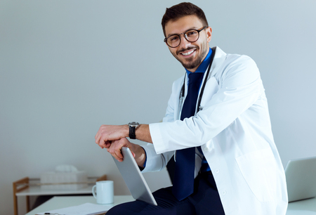 Portrait of confident male doctor smiling and looking at camera in the office.の写真素材